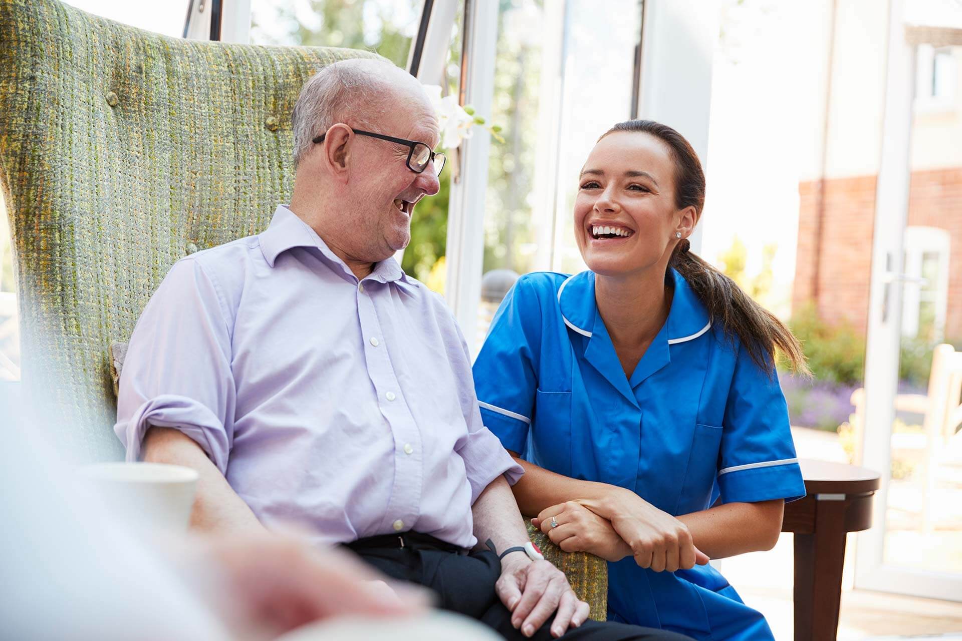 senior-man-sitting-in-chair-and-talking-with-nurse
